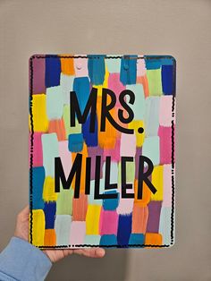 a person holding up a piece of art with the words mrs miller on it