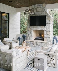 an outdoor living area with furniture and a television on the wall, fireplace in the background