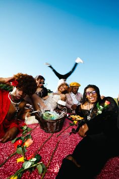 a group of people sitting on top of a bed next to each other in front of a blue sky