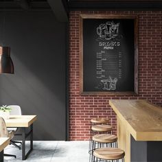 an empty restaurant with brick walls and bar stools in front of the chalkboard