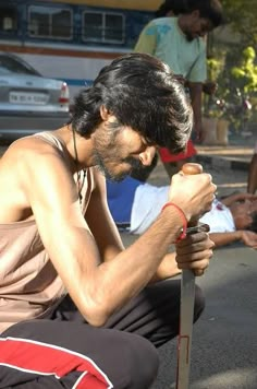 a man sitting on the ground holding a knife