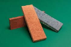 three different colored bricks laying on top of each other in front of a green background