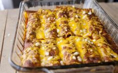 a casserole dish with meat and cheese in it sitting on a wooden table