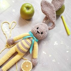 a crocheted stuffed animal laying on top of a table next to an apple