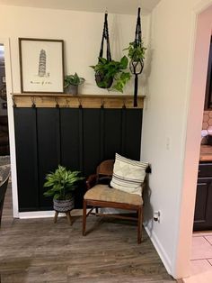 a room with a chair, potted plant and other items on the wall in it