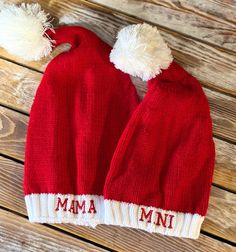 two red hats with white pom - poms on them sitting on a wooden surface