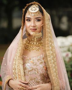 a woman in a wedding outfit with jewelry on her head and veil over her face