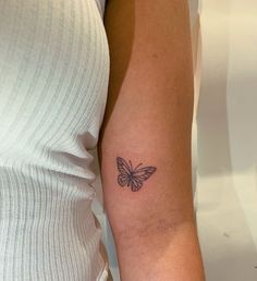 a woman's arm with a small butterfly tattoo on the left side of her arm