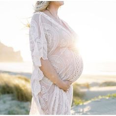 a pregnant woman is standing on the beach