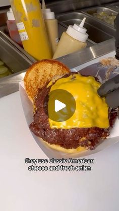 a cheeseburger with meat and mustard is on a plate next to a knife