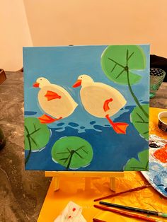 the painting is being displayed on the easel with water lilies and lily pads