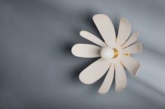 a white flower shaped light fixture on a gray wall next to a blue background with gold accents