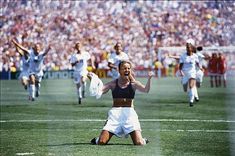 a woman kneeling on top of a soccer field