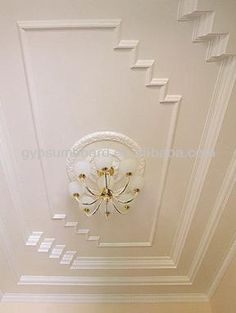 the ceiling in this room is decorated with white and gold trimmings, along with a chandelier