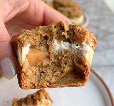 a person holding up a half eaten cookie with cream cheese and walnuts on top