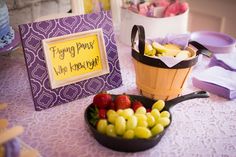 a table topped with a basket filled with fruit next to a sign that says frying pans we know it