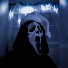 a person wearing a ghost mask with its mouth open and tongue out in front of a window