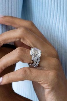 a woman's hand holding an engagement ring with a diamond in the middle and two bands around it