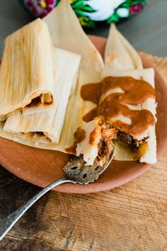 an enchilada is on a plate with a fork next to some sauce