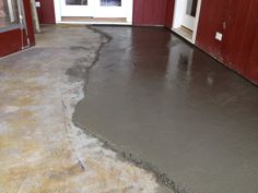 a cement floor is being poured in front of a red building with white doors and windows