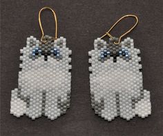 two pieces of plastic bead are sitting on a table next to each other, one with blue eyes and the other has a white cat