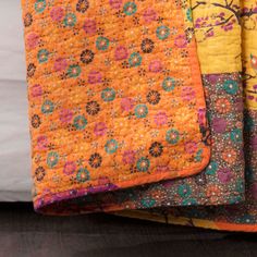 three quilts are stacked on top of each other, one has an orange and blue flower pattern