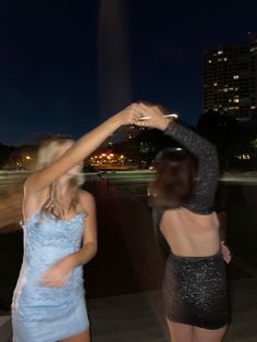 two women in short dresses dancing at night