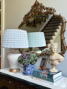 there is a mirror, lamp and vase on the table in front of the stairs