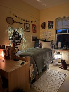 a bedroom with yellow walls and pictures on the wall above the bed, along with a teddy bear