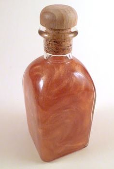 a small glass bottle with a wooden stopper on it's top, sitting on a white surface