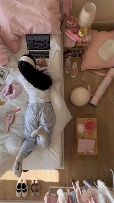 a woman laying in bed with her laptop and other items on the floor next to her