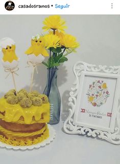 there is a cake with yellow icing and flowers in the vase next to it