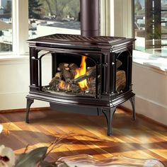 a wood burning stove in the middle of a living room with a large window behind it