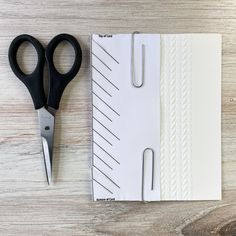 a pair of scissors sitting on top of an open notepad next to a clipboard