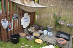 an outdoor area with pots and pans on the ground next to a wooden fence