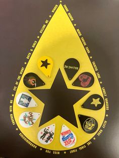 a star is surrounded by various badges and magnets on a black surface with yellow border