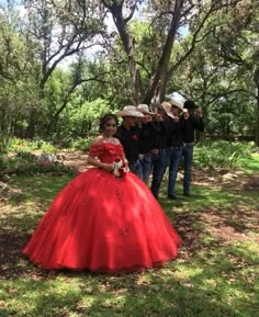 a woman in a red dress standing next to other people