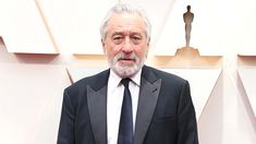 an older man in a suit and tie posing for the camera on the oscars red carpet