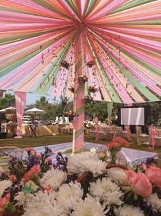 an open umbrella with flowers in the foreground and other decorations on the ground behind it