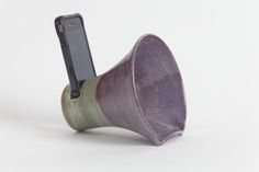 a purple and green cup with a cell phone in it's holder on a white background