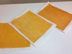 three pieces of yellow paper sitting on top of a white table next to each other