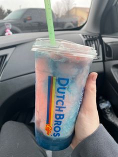 a person holding up a drink in their hand while sitting in the driver's seat of a car