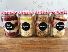 four jars filled with food sitting on top of a wooden table