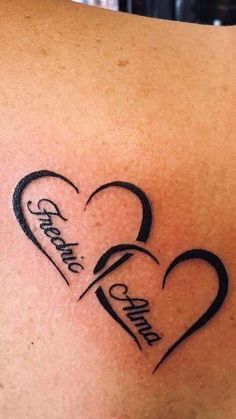 a couple of hearts with the names of two people in them on their back shoulder