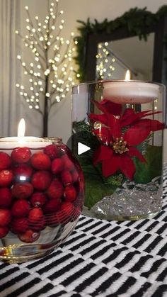 two glass vases filled with red balls on top of a black and white table cloth