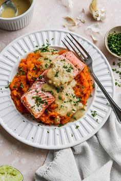 a white plate topped with salmon and mashed potatoes next to two bowls of sauce