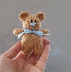 a hand holding a small knitted teddy bear