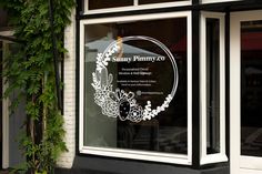 the window is decorated with white flowers and leaves, along with an etched glass sign that reads sunny primary co