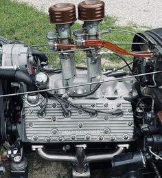 an engine is shown on the ground in front of some grass and gravel, with two brown wires running through it