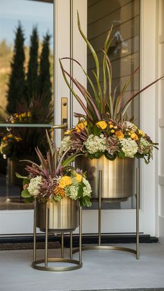 two metal planters with flowers in them